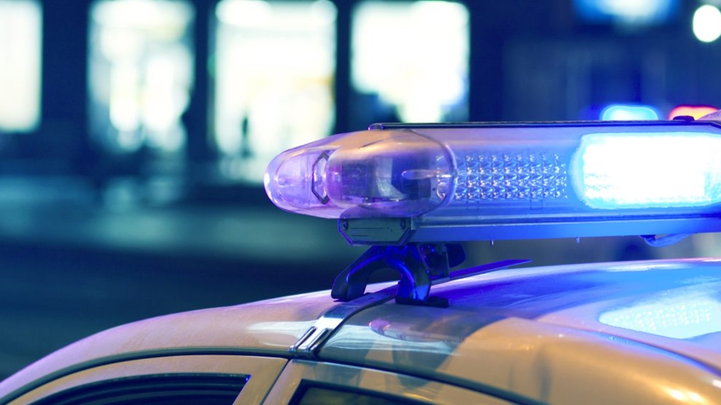 Blue light flasher atop of a police car. City lights on the background.