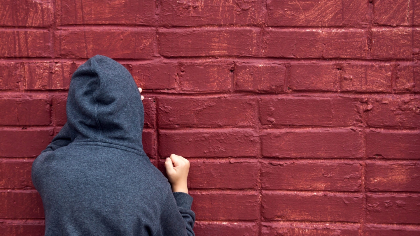 Worried depressed sad teen boy (child) crying near brick wall