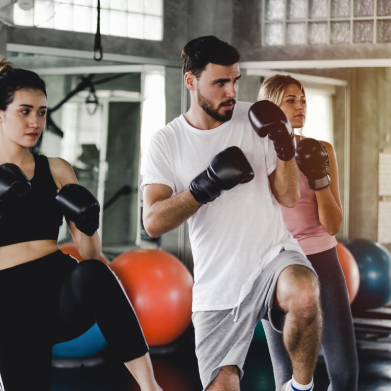 Sporty woman and men with the back boxing gloves training at the gym