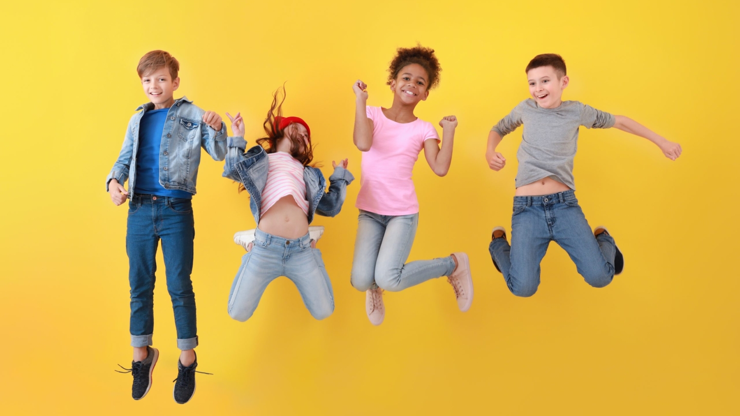 Jumping children in jeans near color wall