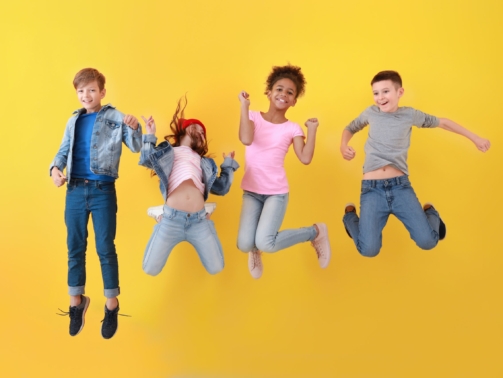 Jumping children in jeans near color wall